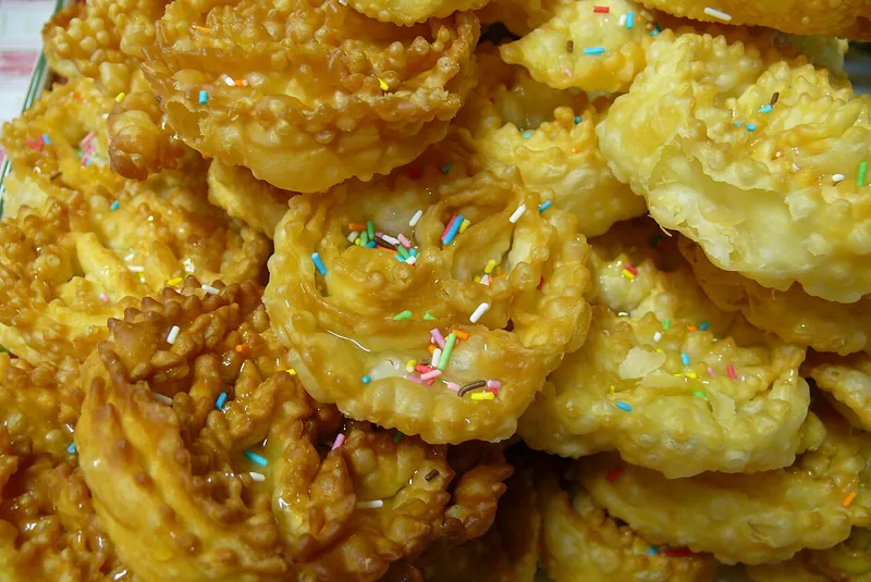 Cartellate appena fatte, arrotolate e dorate, su un vassoio.