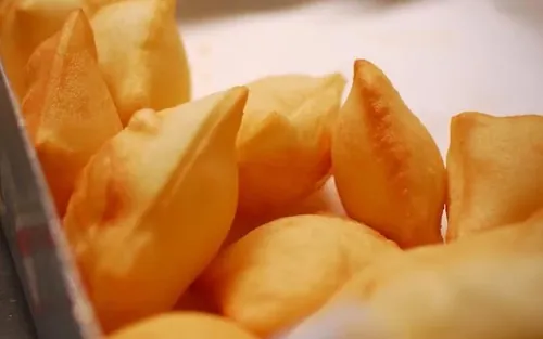 Crescentine appena fritte, ancora gonfie, in un vassoio con la carta.
