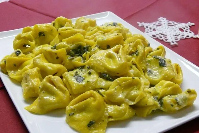 Tortelloni burro e salvia serviti su un vassoio bianco.